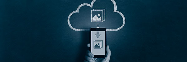 Ein Handy vor einer auf einer Tafel gemalten Cloud als Symbol für Downloads